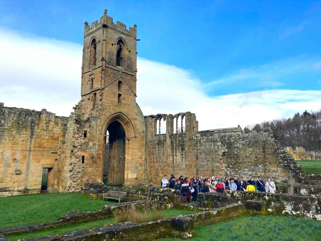 Students at Mount Grace priory, stood in a group before the bell tower of the church